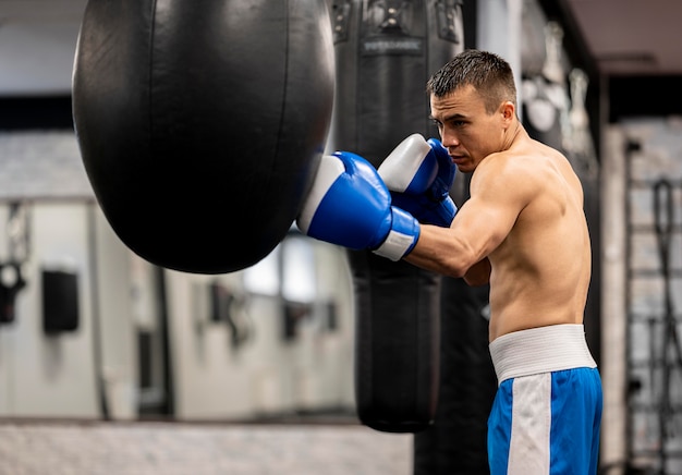 Side view of shirtless male boxer practicing