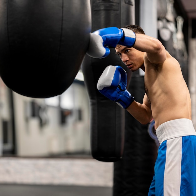 Free photo side view of shirtless male boxer training