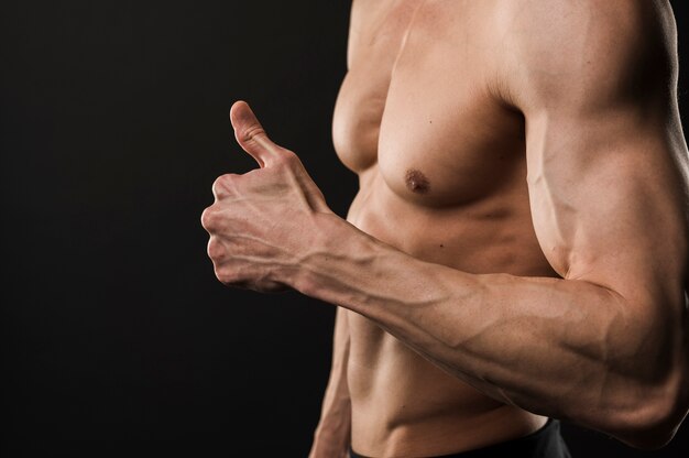 Side view of shirtless muscled man giving thumbs up