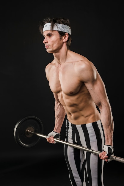 Free photo side view of shirtless muscled man lifting weights