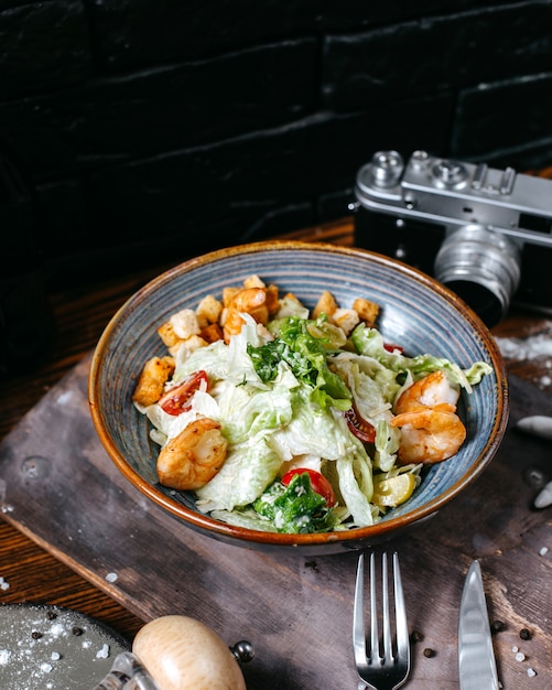 Foto gratuita vista laterale dell'insalata di caesar del gamberetto con i pomodori ciliegia in ciotola