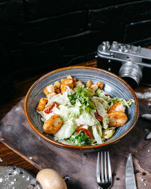 Side view of shrimp caesar salad with cherry tomatoes in bowl