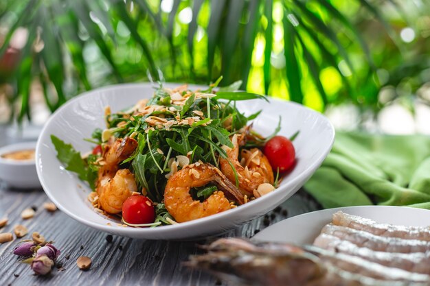 Side view shrimp salad grilled shrimps with tomato arugula and peanut on a plate