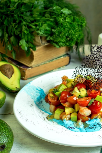 Vista laterale dell'insalata di gamberi con avocado e pomodorini in ciotola