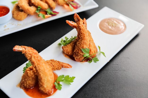 Side view shrimps in batter with sauces on a stand