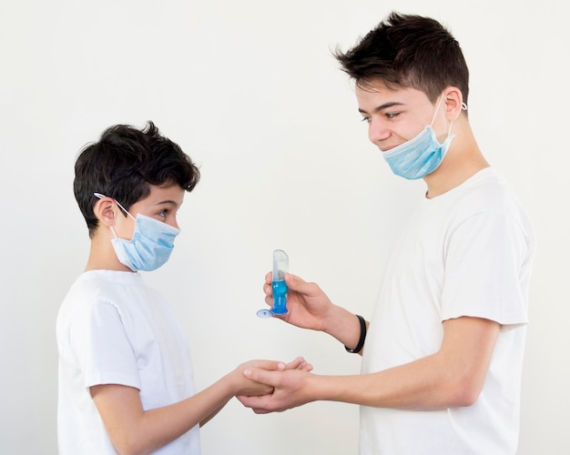 Side view siblings using hand sanitizer