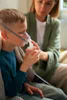 Free photo side view sick kid using a nebulizer