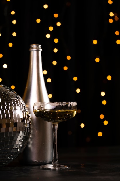 Side view silver bottle with champagne and party globe