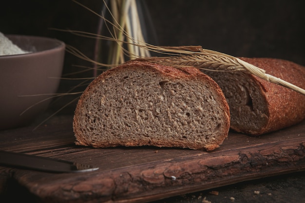 Side view slice of a bread on cutting board and dark brown.