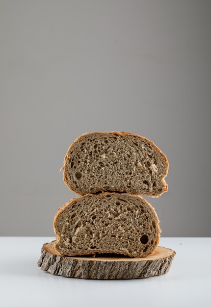 Side view sliced bread on wood on white surface. vertical space for text