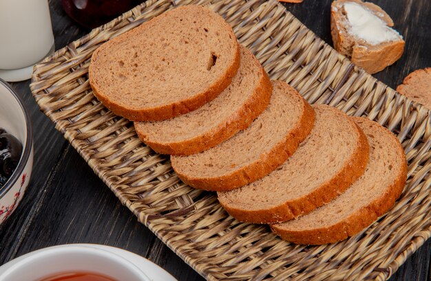 Side view of sliced rye bread in basket plate with milk olive on wooden table