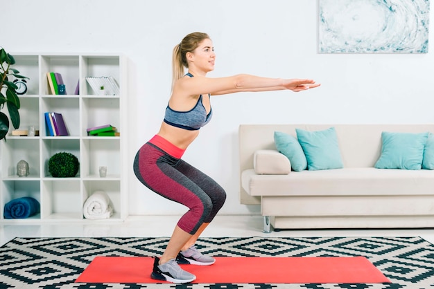 Side view of slim fitness young woman practicing exercise at home