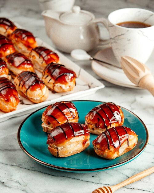 Side view of small eclair covered with caramel served with tea