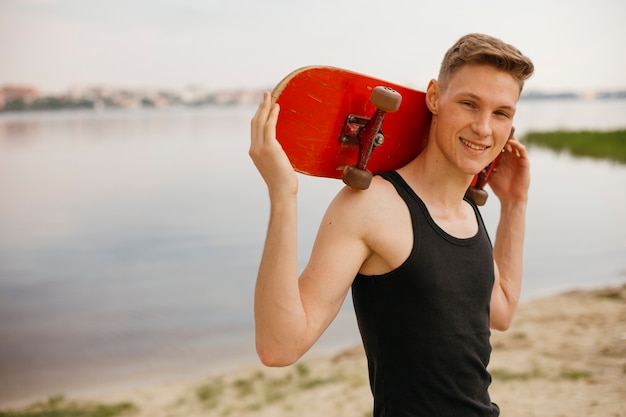 Free photo side view smiley boy posing with skateboard