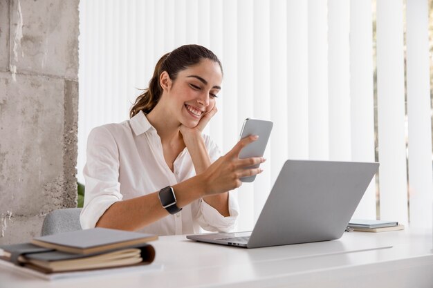 Side view of smiley businesswoman with smartphone and laptop