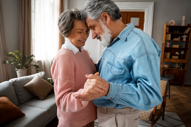 Free photo side view smiley couple dancing at home