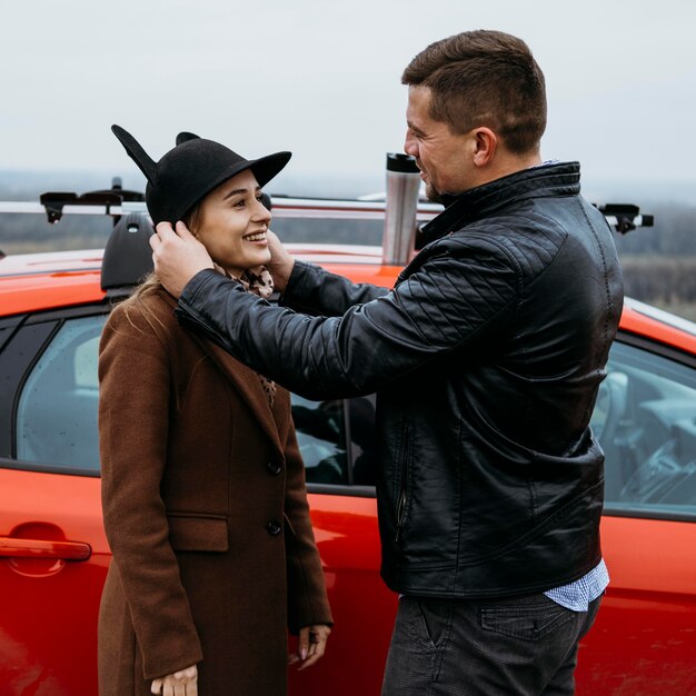 Side view of smiley couple outdoors next to car