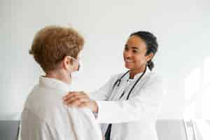 Free photo side view smiley doctor talking to patient