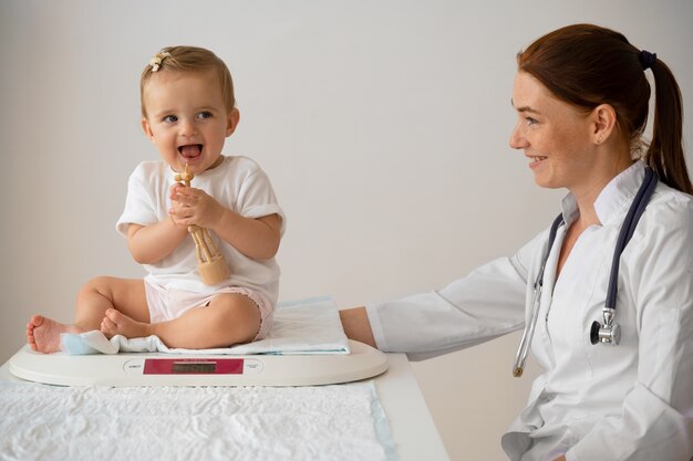 side view smiley doctor weighing babies