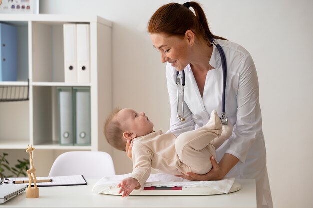 Side view smiley doctor weighing babies