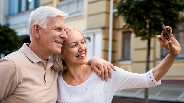 Side view of smiley elder couple outdoors taking a selfie