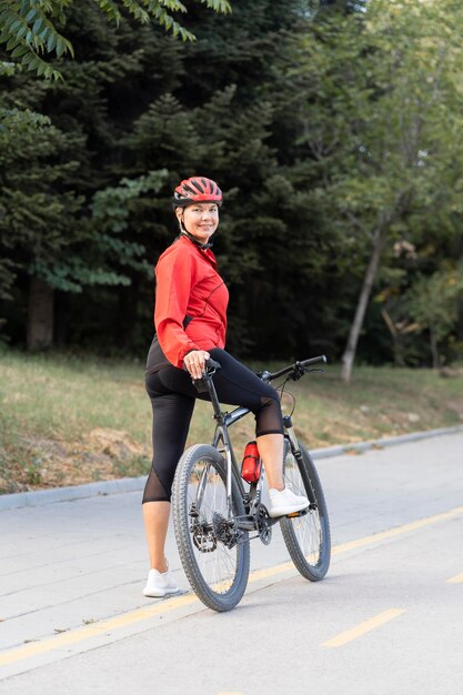 Side view of smiley elder woman outdoors riding bicycle