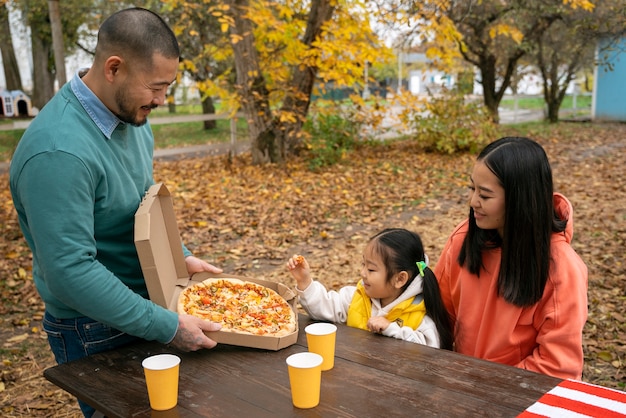 Side view smiley family with pizza