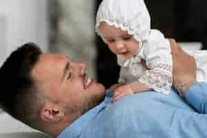 Free photo side view smiley father holding baby