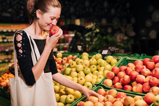 Side view smiley female smelling an apple