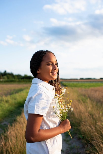 Side view smiley girl holding flowers