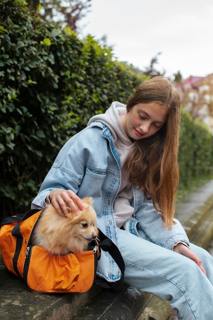 Foto gratuita ragazza sorridente di vista laterale che si siede con il cane