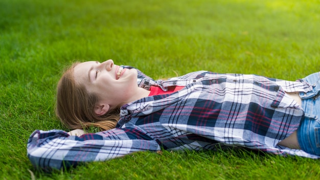 Free photo side view smiley girl staying on grass