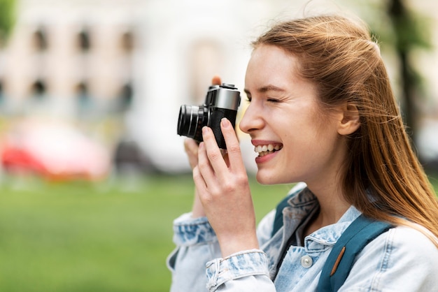 Free photo side view smiley girl taking a picture