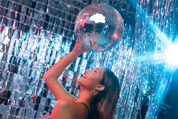 Foto gratuita ragazza sorridente di vista laterale con la palla da discoteca