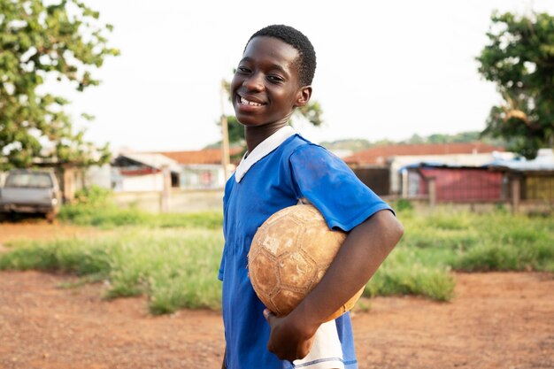 Side view smiley kid holding ball