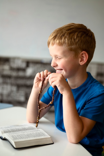 Free photo side view smiley kid praying at sunday school