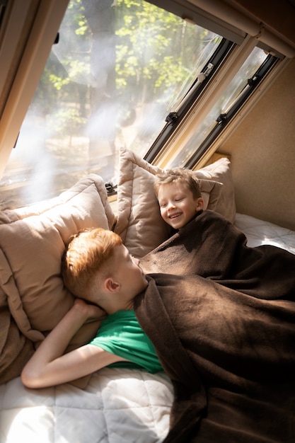 Free photo side view smiley kids laying in bed