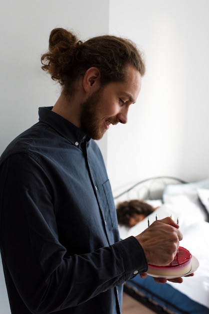 Free photo side view smiley man holding cake