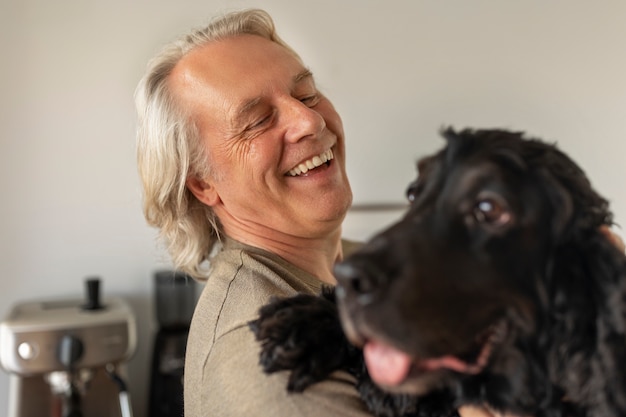 Foto gratuita cane della holding dell'uomo di smiley di vista laterale