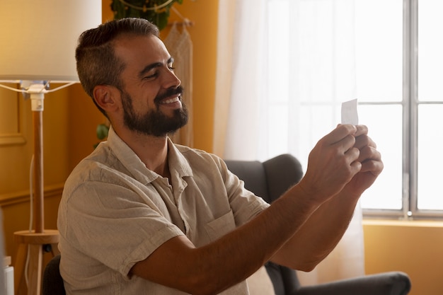 Foto gratuita uomo sorridente di vista laterale che tiene il biglietto della lotteria