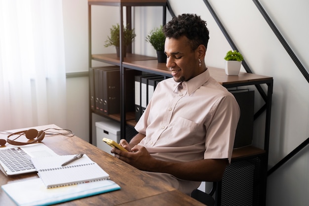 Free photo side view smiley man holding smartphone