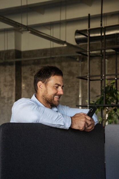 Side view smiley man holding smartphone