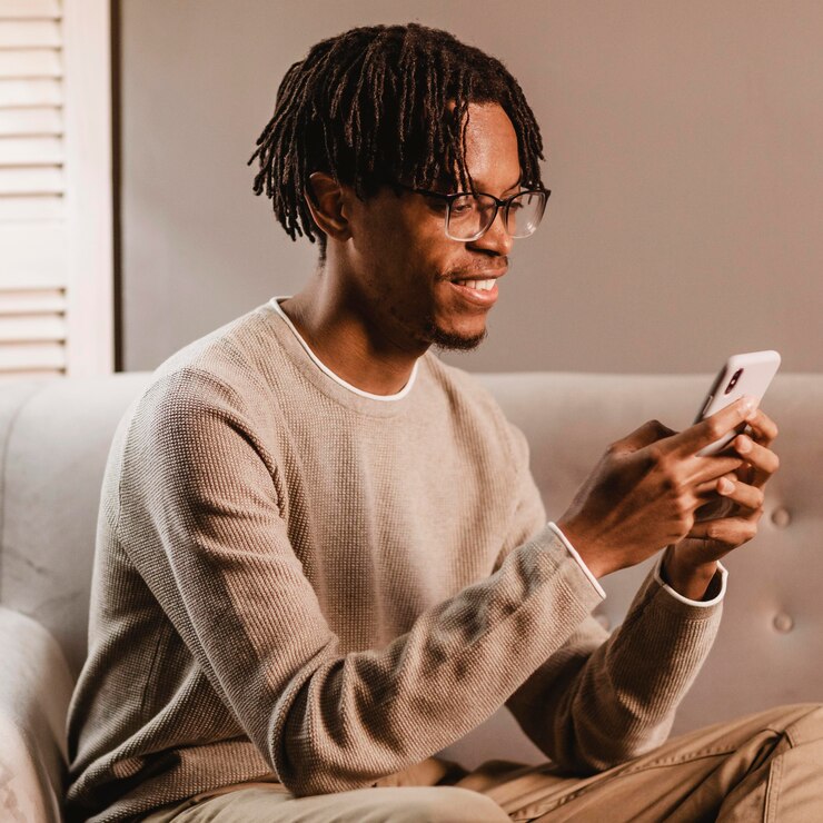 Free Photo side view of smiley man at home using smartphone