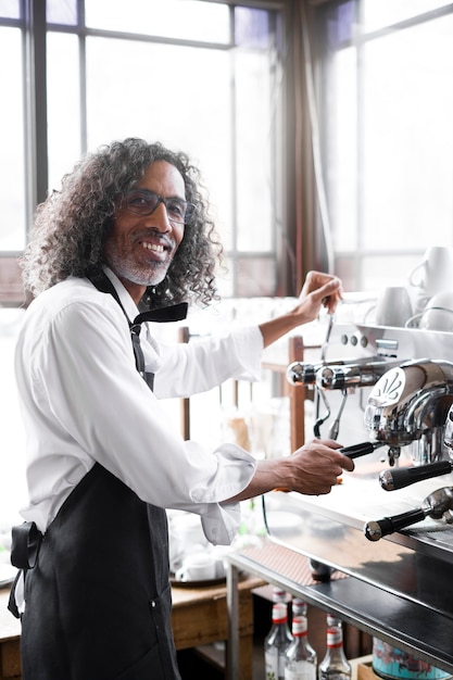 Free photo side view smiley man making coffee