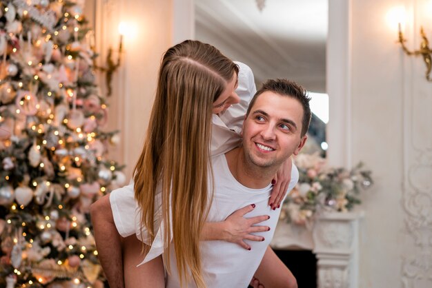 Side view of smiley man piggybacking woman