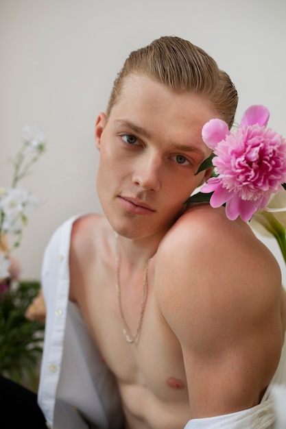 Free photo side view smiley man posing with flowers