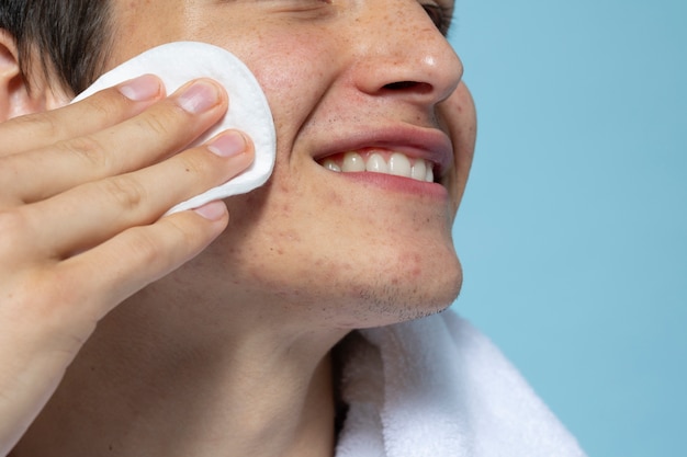 Side view smiley man using cotton pad