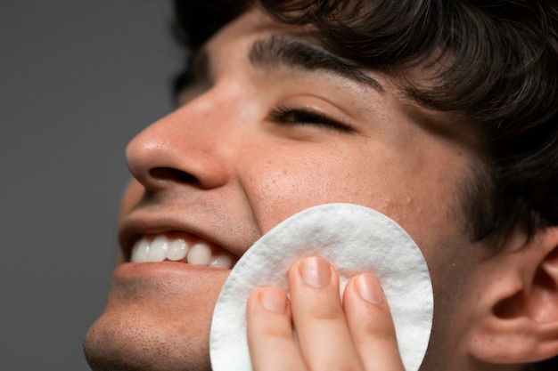 Side view smiley man using cotton pad