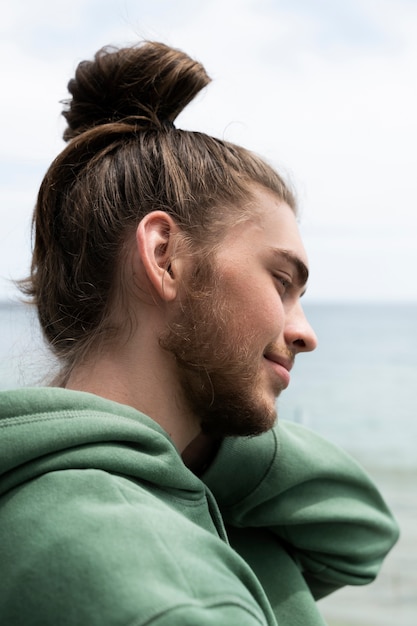 Free photo side view smiley man with messy bun