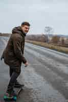 Foto gratuita vista laterale dell'uomo di smiley con lo skateboard sulla strada